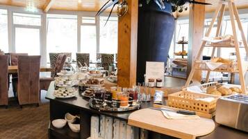 A buffet setup with various food items and a coffee station in a well-lit room with wooden accents and large windows.