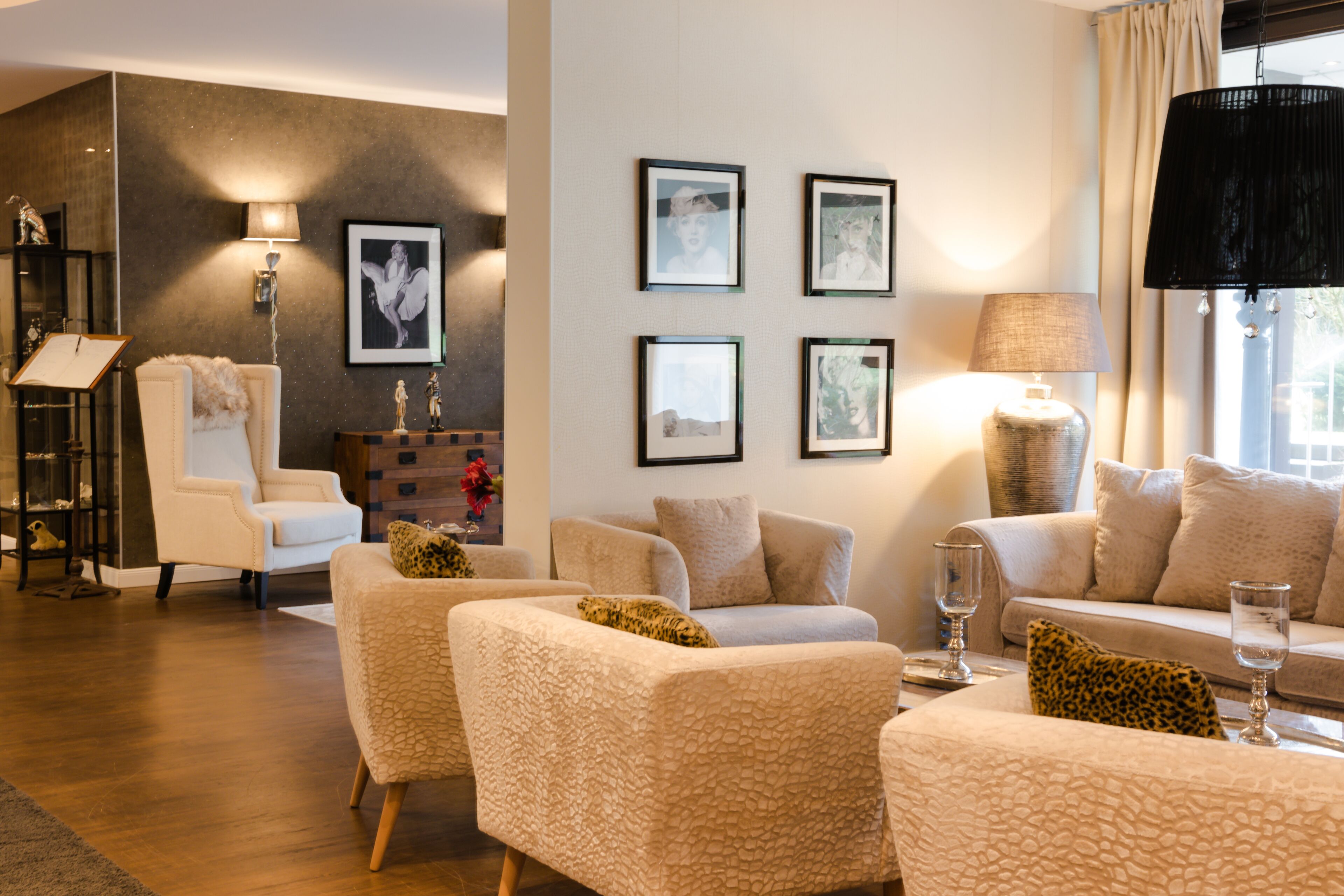 A modern living room with a sofa set, a chair, a lamp, and framed pictures on the wall.