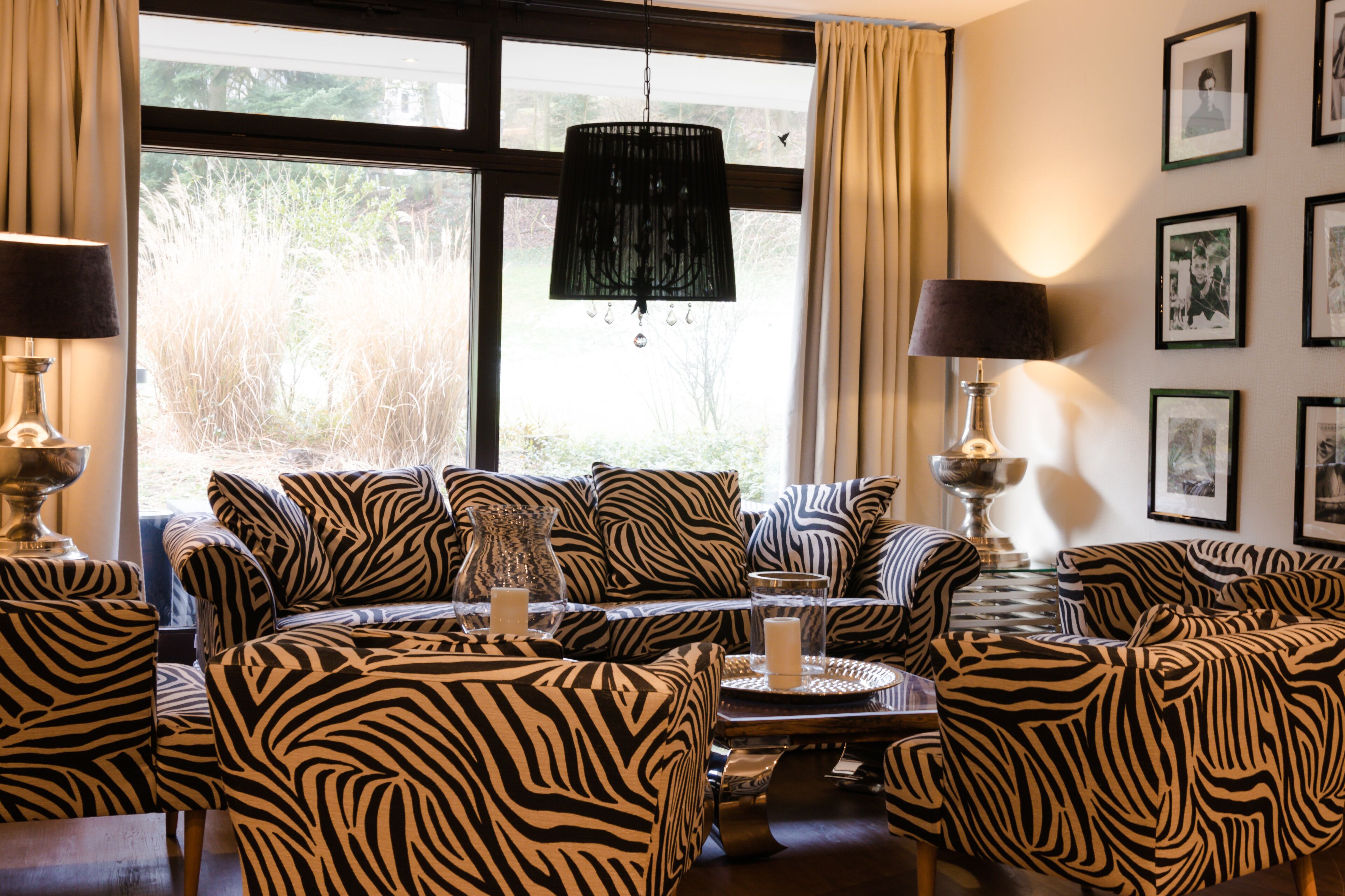 A living room with zebra-patterned furniture, a chandelier, and framed pictures on the wall.