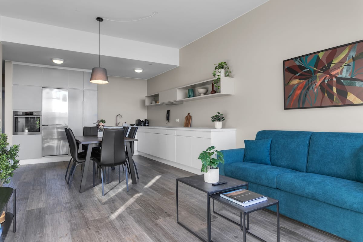 Una cocina moderna con comedor, un sofá azul y una mesa de centro.