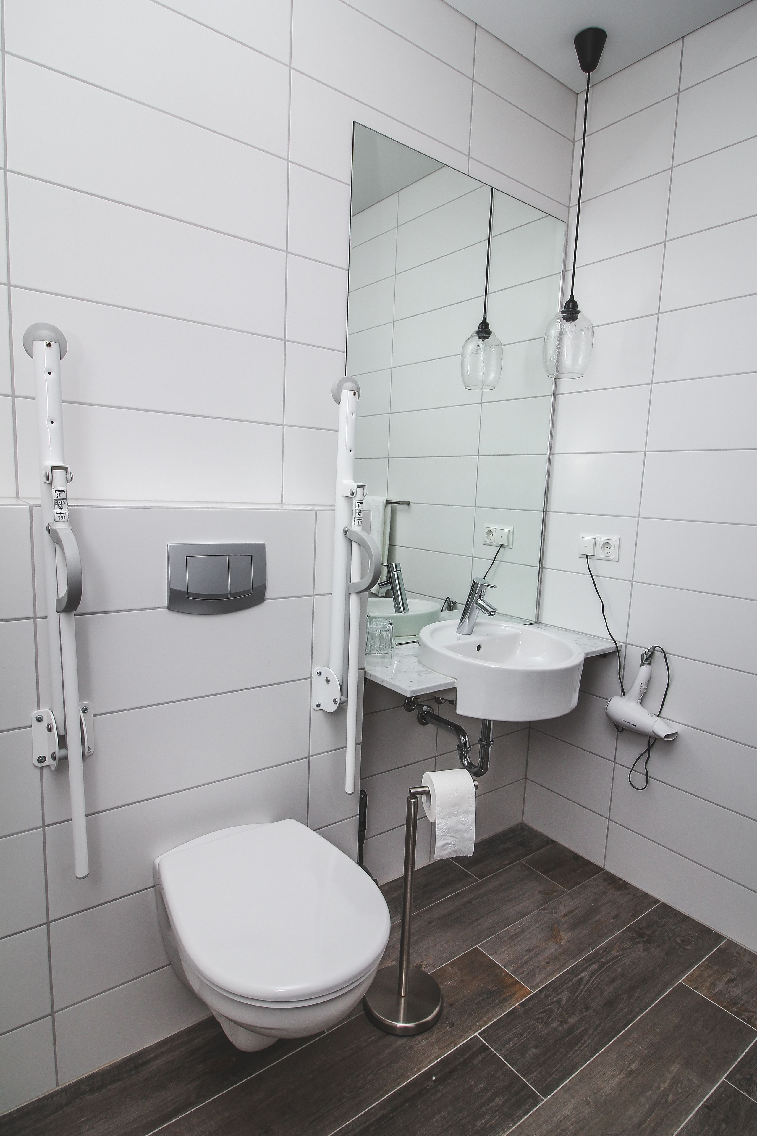 Ein modernes Badezimmer mit Toilette, Waschbecken, Spiegel und Handtuchhalter.