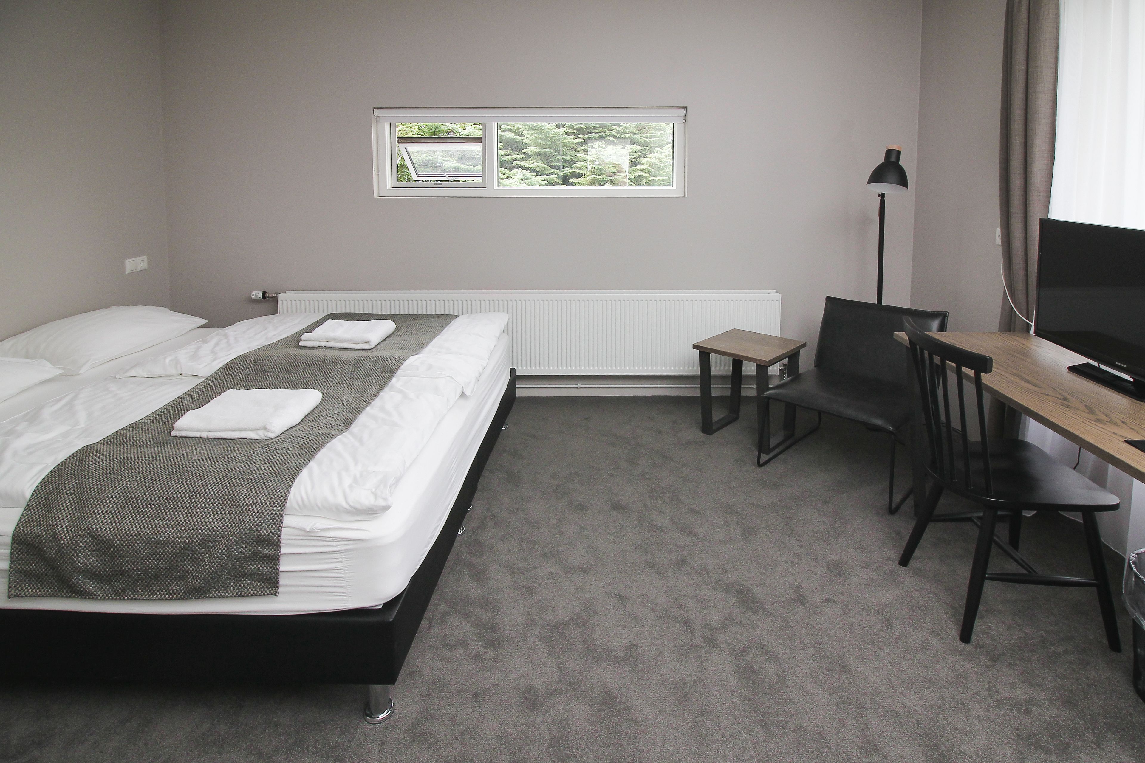 Ein Schlafzimmer mit Bett, Schreibtisch, Stuhl und Fenster.