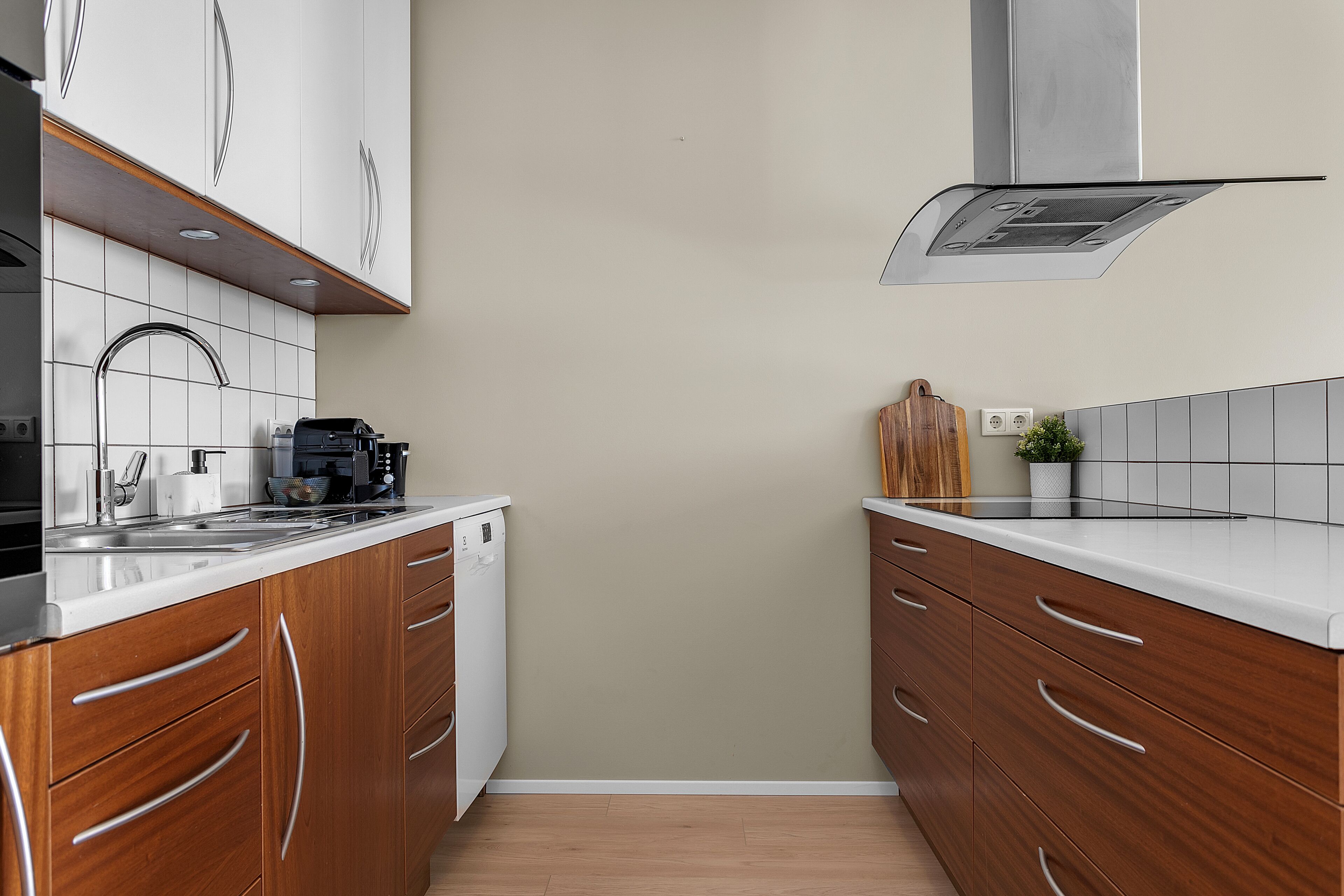 A modern kitchen with wooden cabinets, a stainless steel range hood, and a white countertop.