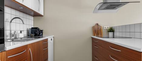A modern kitchen with wooden cabinets, a stainless steel range hood, and a white countertop.