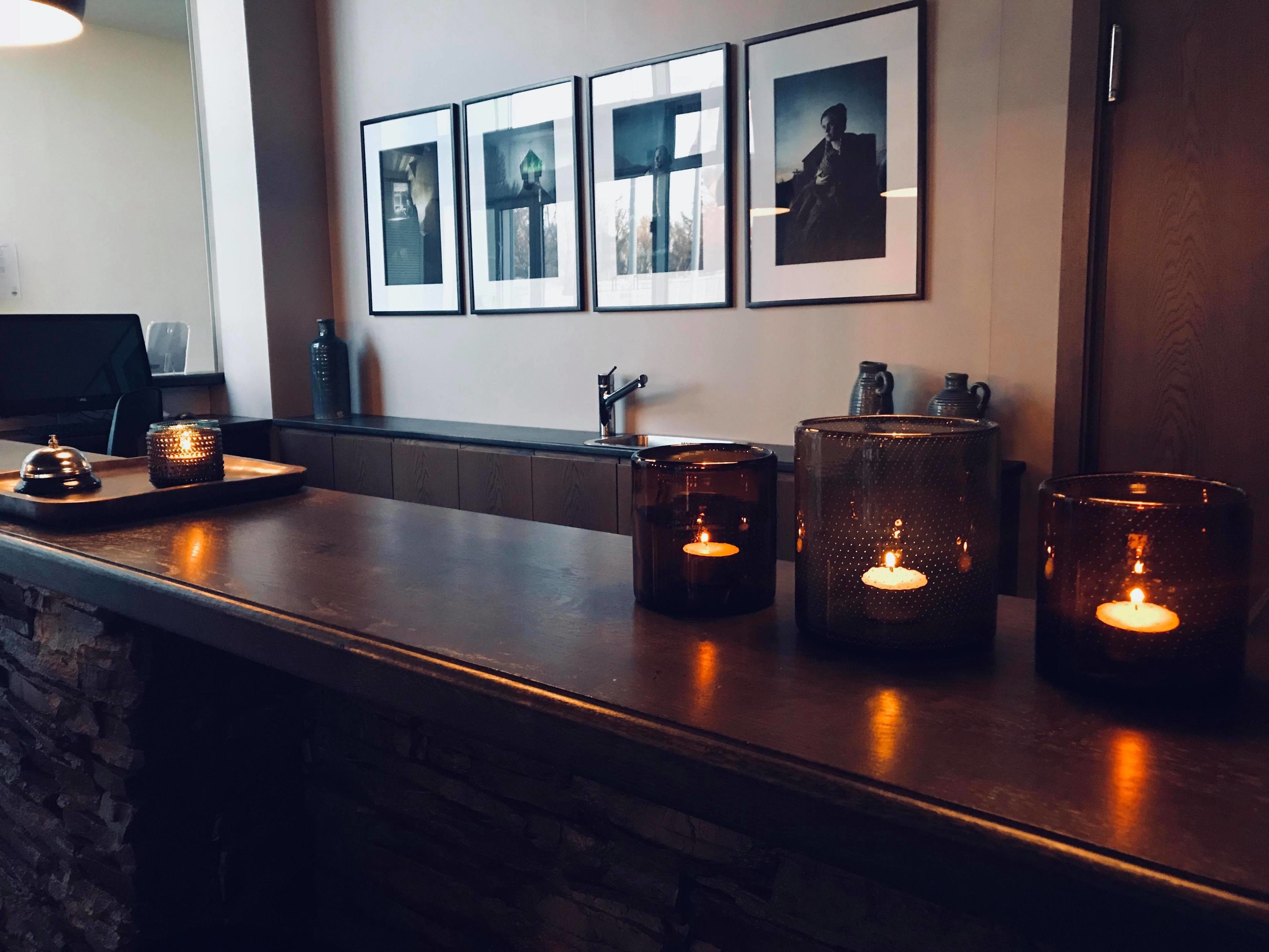 A bar area with a stone counter, three lit candles, and framed photographs on the wall.