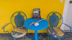 A small table with two chairs, a stack of books, and a decorative item on the table. - Anastasia Studios (Kefalonia)