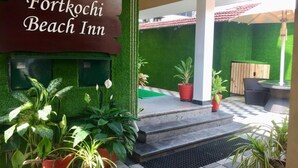 The entrance of Fort Kochi Beach Inn with a signboard, potted plants, and outdoor seating. - Fortkochi Beach Inn (Kochi)