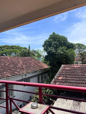 A view from a balcony with red railings, overlooking a residential area with houses that have red-tiled roofs and lush greenery. - Fortkochi Beach Inn (Kochi)