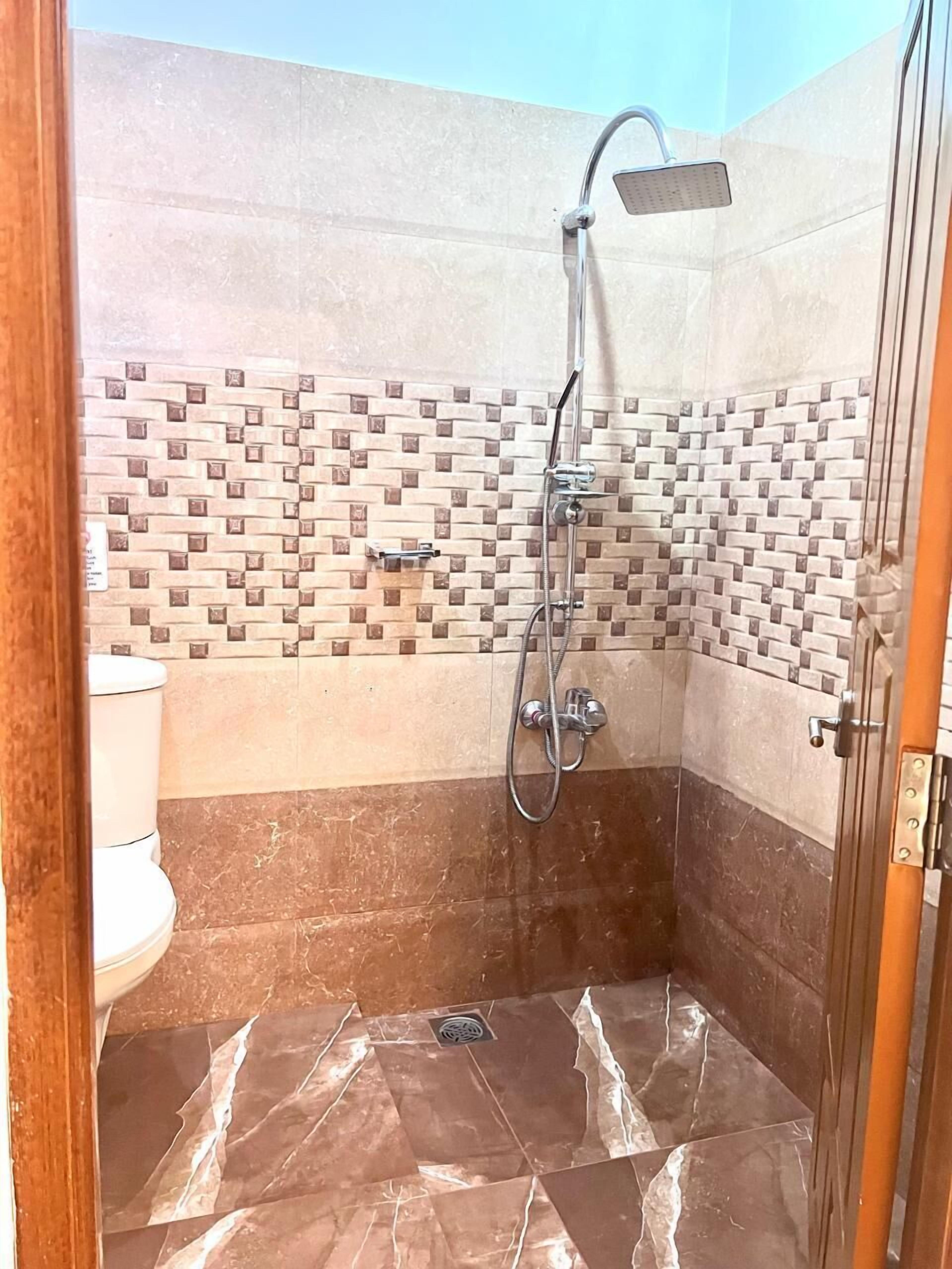 A shower with a handheld showerhead and a wall-mounted faucet.