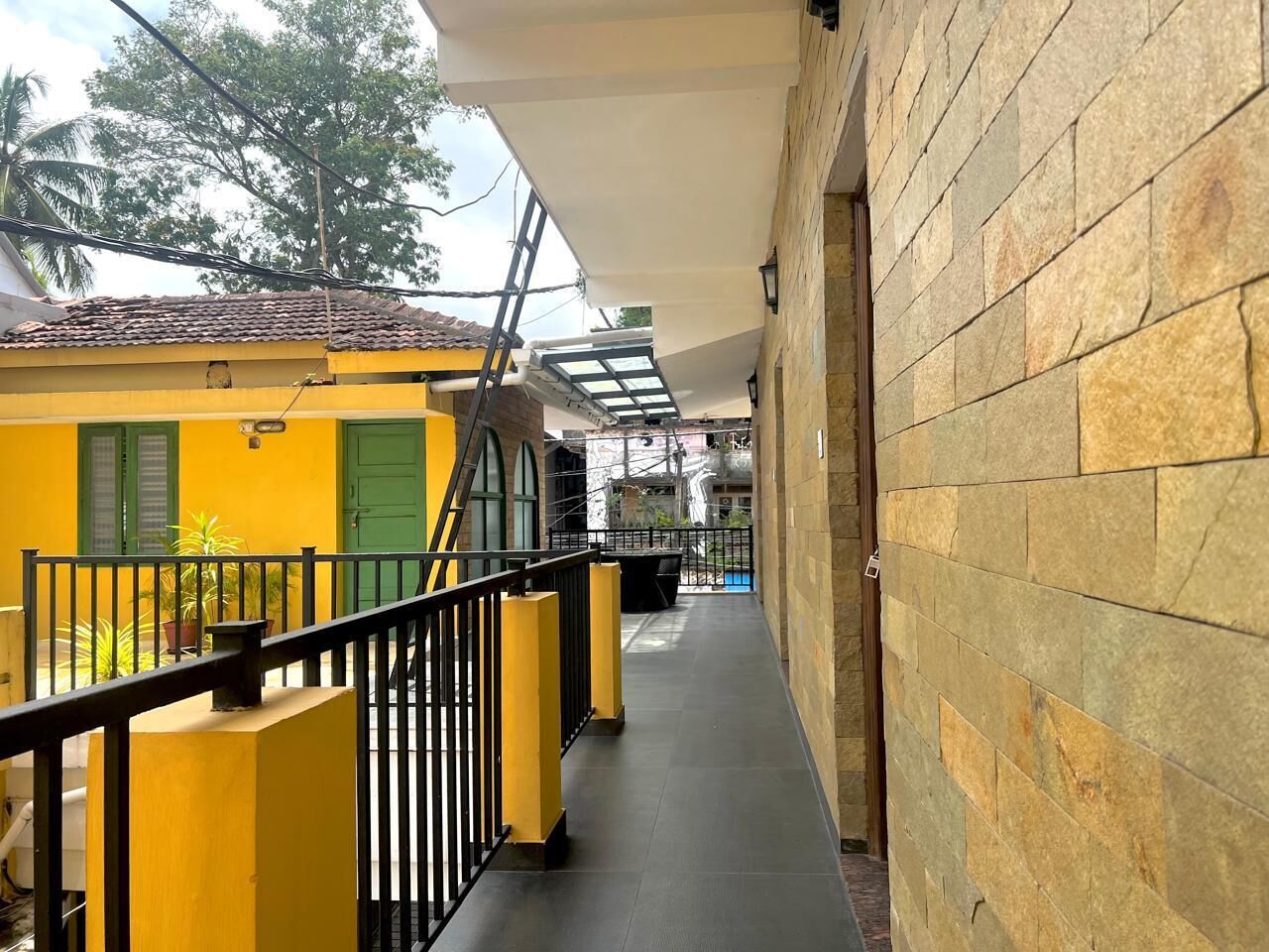 A narrow corridor with a yellow building on one side and a stone wall on the other.