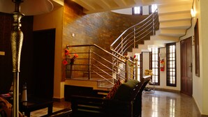 A spacious lobby with a marble floor, a staircase with metal railings, and a brick wall. - Fortkochi Beach Inn (Kochi)
