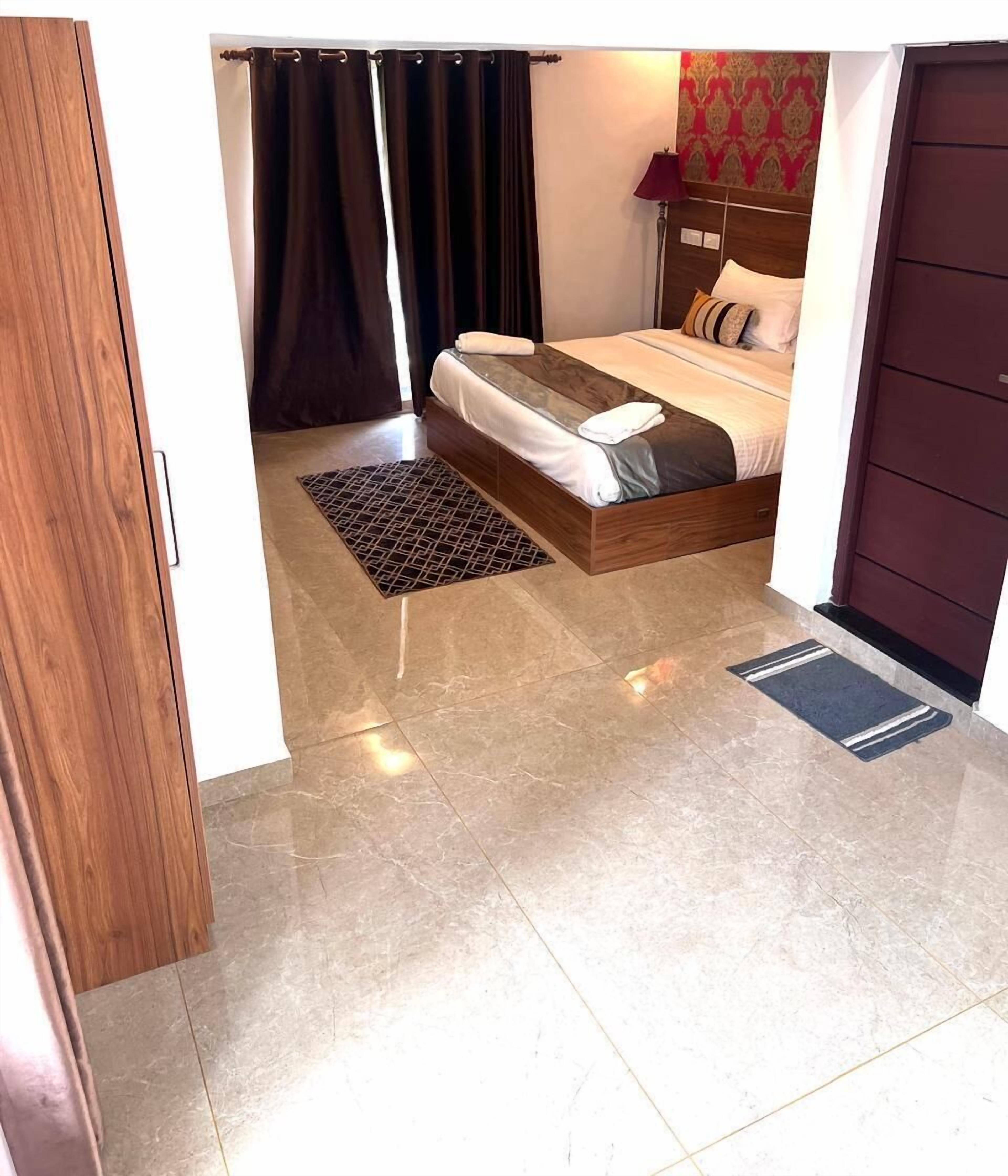 Un dormitorio con cama, mesita de noche, lámpara y alfombra estampada.