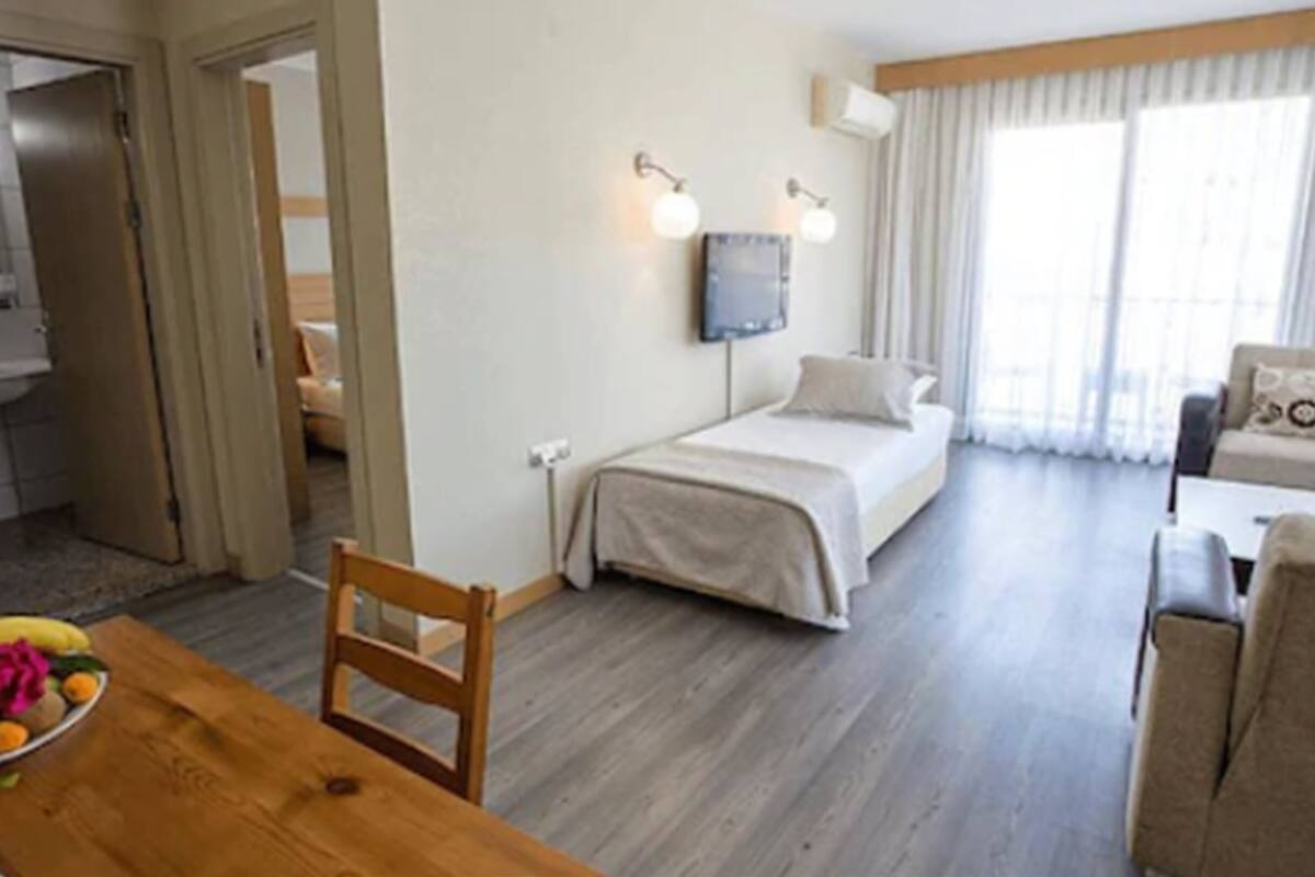 A hotel room with a bed, a desk, and a chair. There is a bathroom visible through an open door.