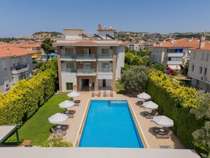 A multi-story hotel with a swimming pool, outdoor seating, and a view of the surrounding neighborhood. - Cilek Marina Hotel (Cesme)