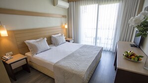 Habitación de hotel con una cama grande, una mesita de noche con teléfono, un escritorio con computadora y un florero.
