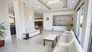 Un moderno vestíbulo de hotel con una recepción, zona de estar y vistas a la ciudad.