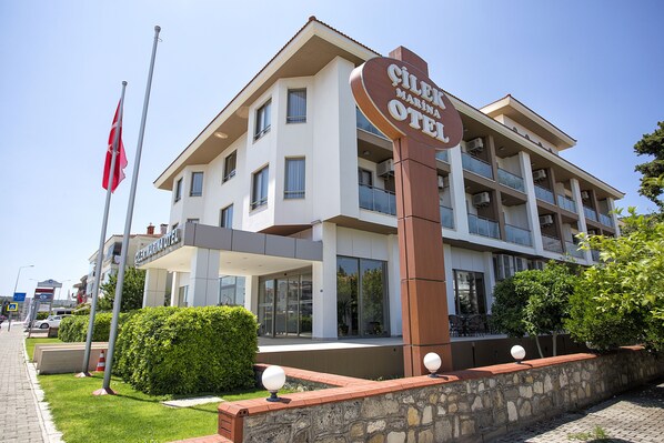 Un hotel con un cartel llamativo, varios balcones y un jardín bien cuidado.