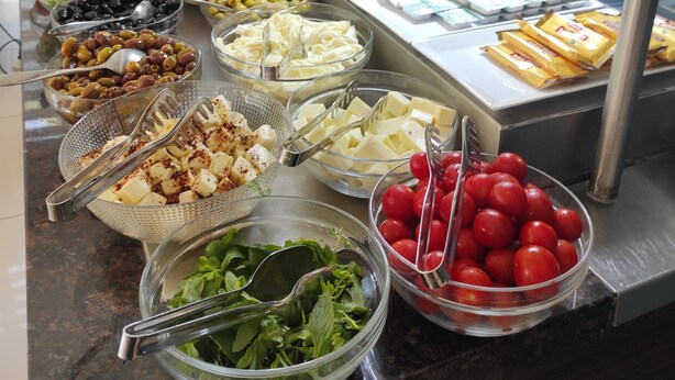 Un bufé con diversas opciones de comida, incluyendo frutas, quesos y salsas.
