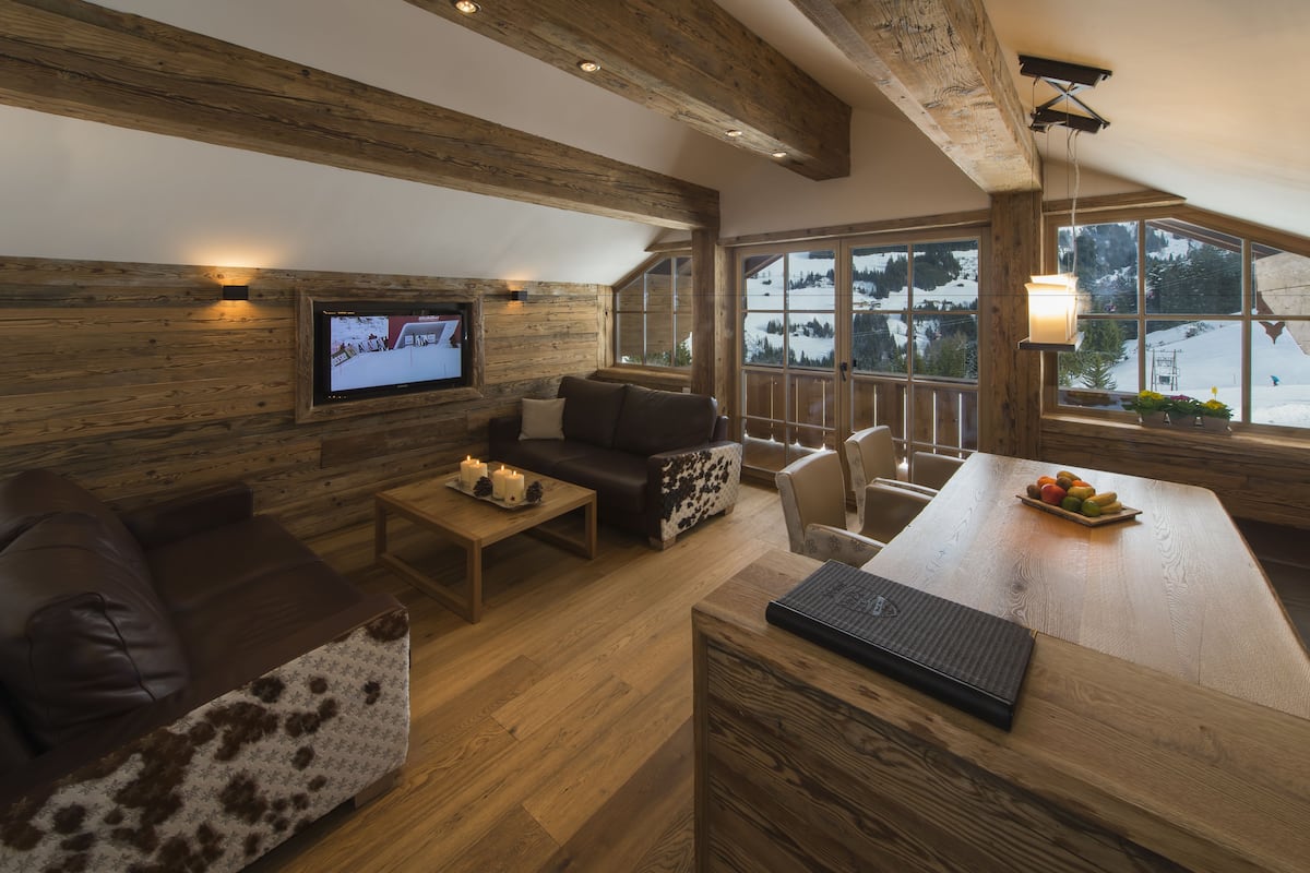 Un interior de cabaña acogedor con detalles de madera, un televisor, un sofá, una mesa de centro y un comedor con frutero.