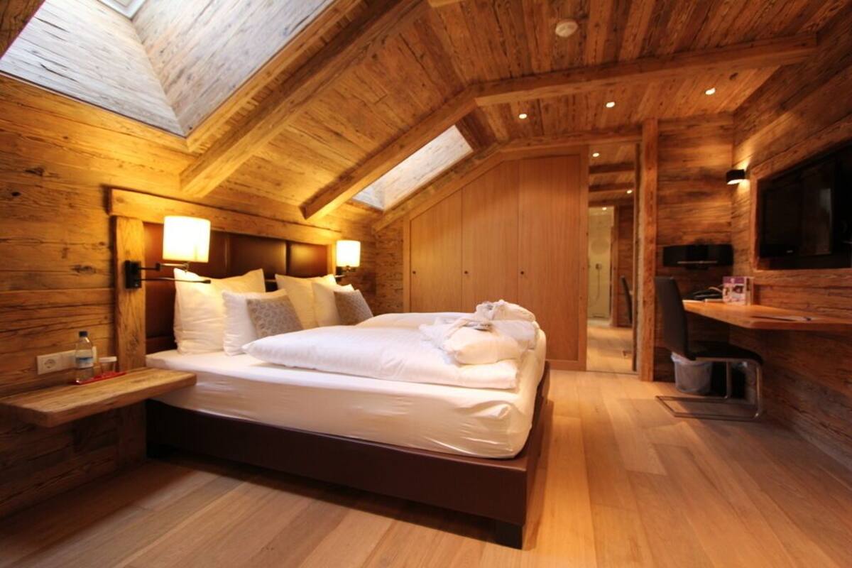 Un interior de madera con una cama, lámparas de noche y un televisor.