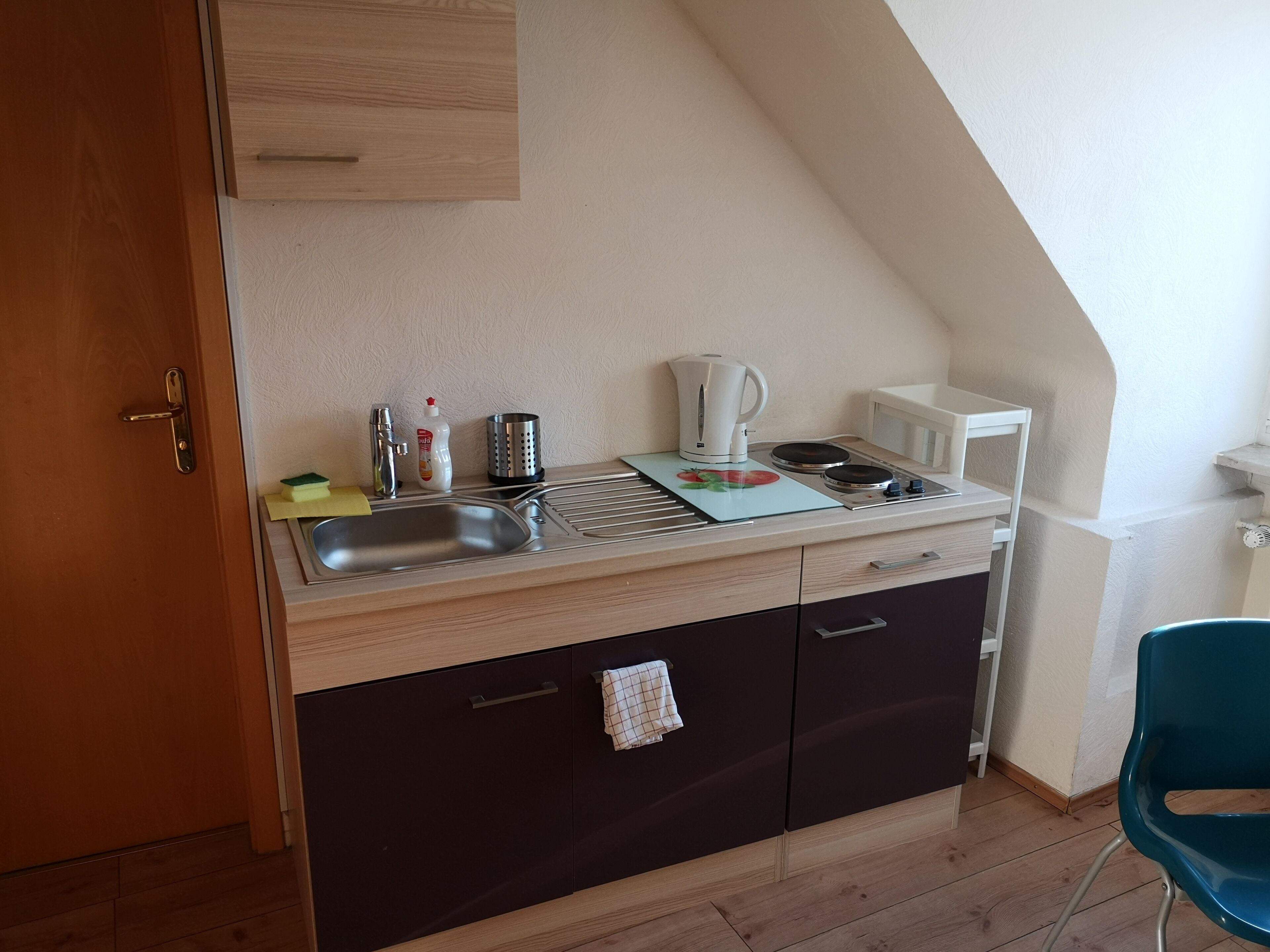 A compact kitchenette with a sink, stove, and storage cabinets.