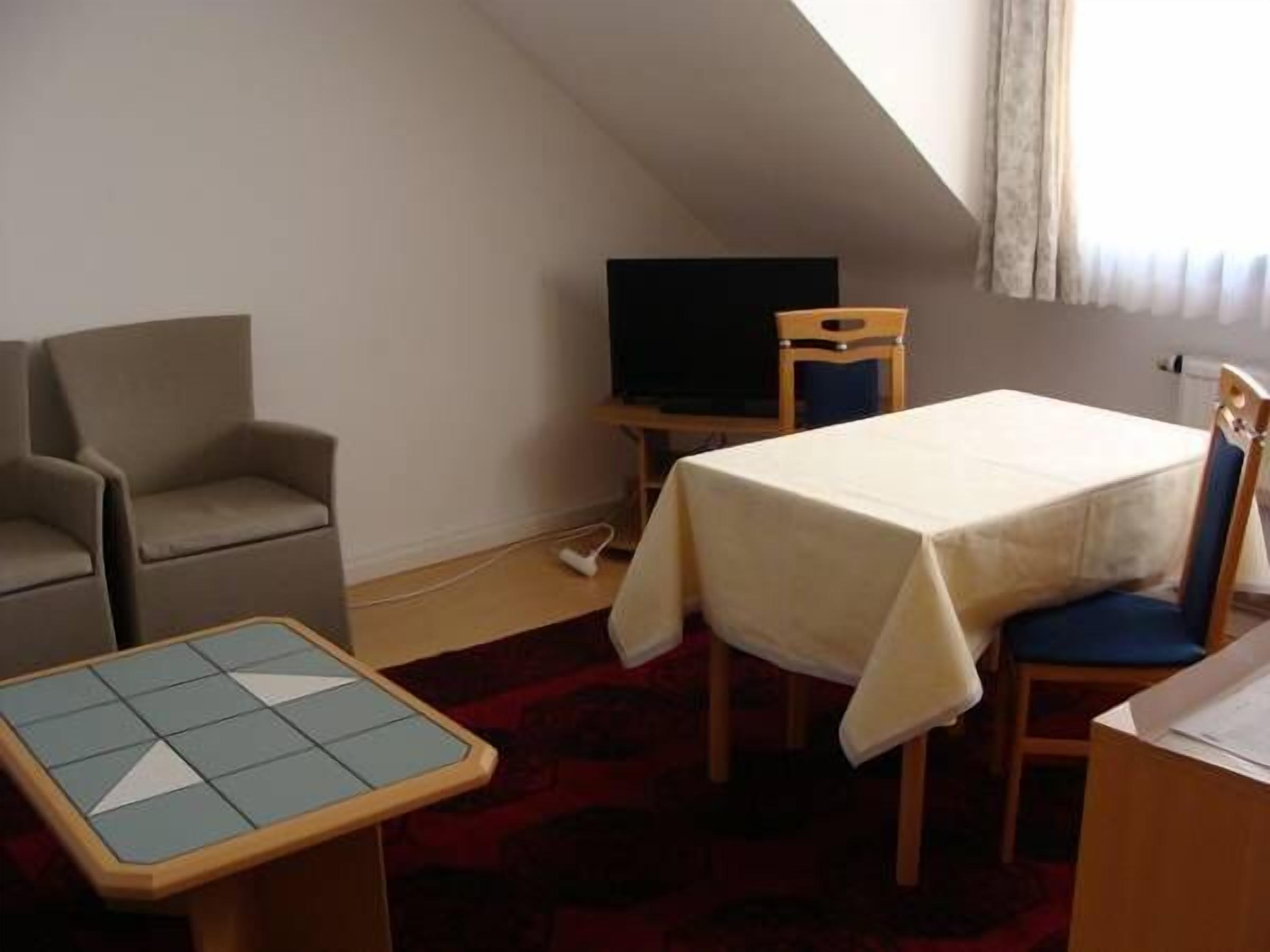 Una habitación pequeña y acogedora con una cama individual, una silla, una mesa y un televisor.