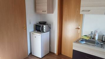 Una cucina compatta con frigorifero, forno a microonde e lavandino.