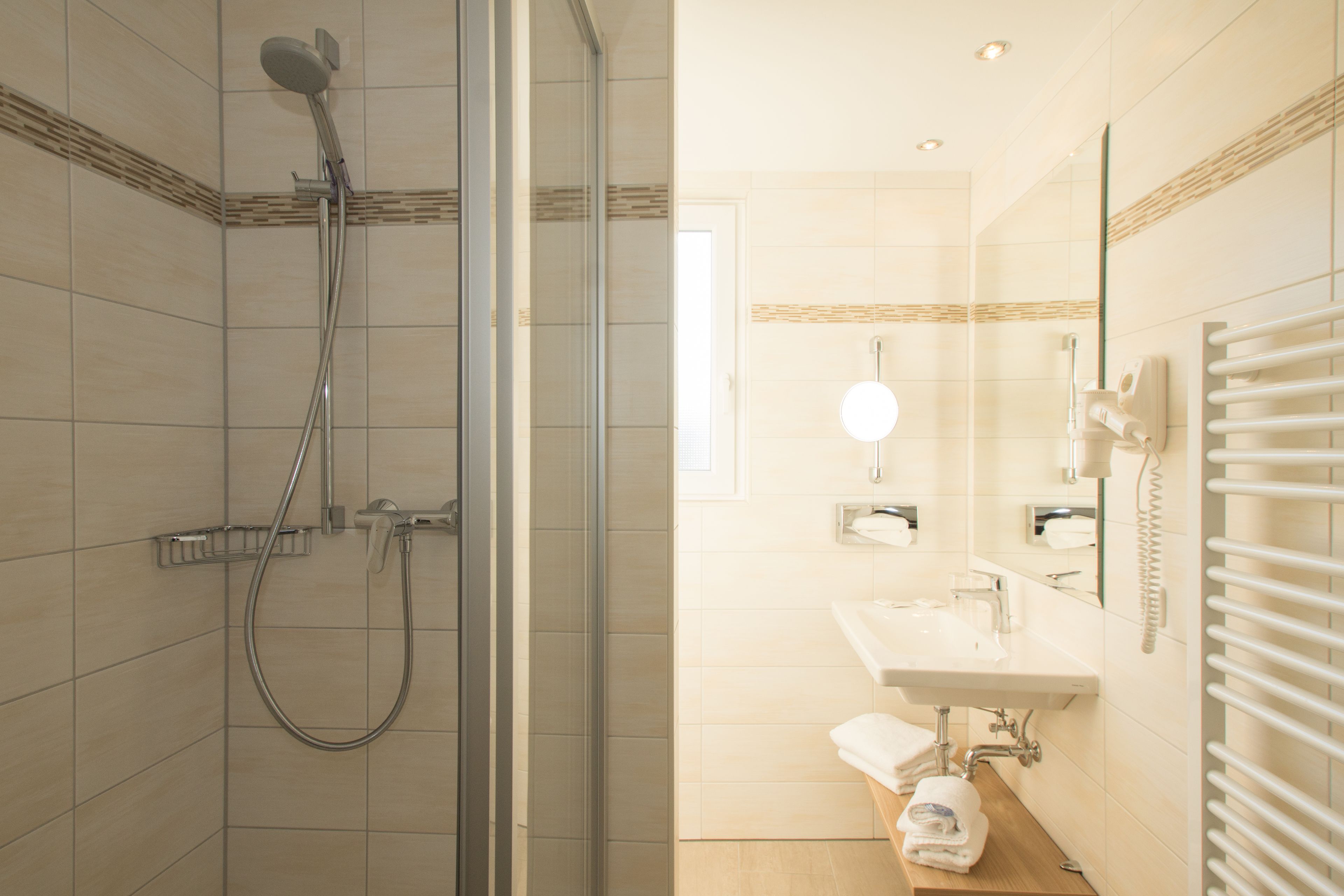 A modern bathroom with a glass-enclosed shower, a sink with a mirror, and a towel rack.