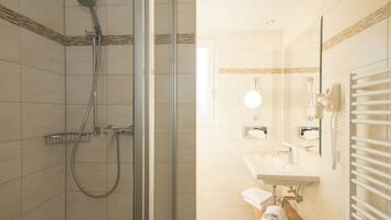 A modern bathroom with a glass-enclosed shower, a sink with a mirror, and a towel rack.