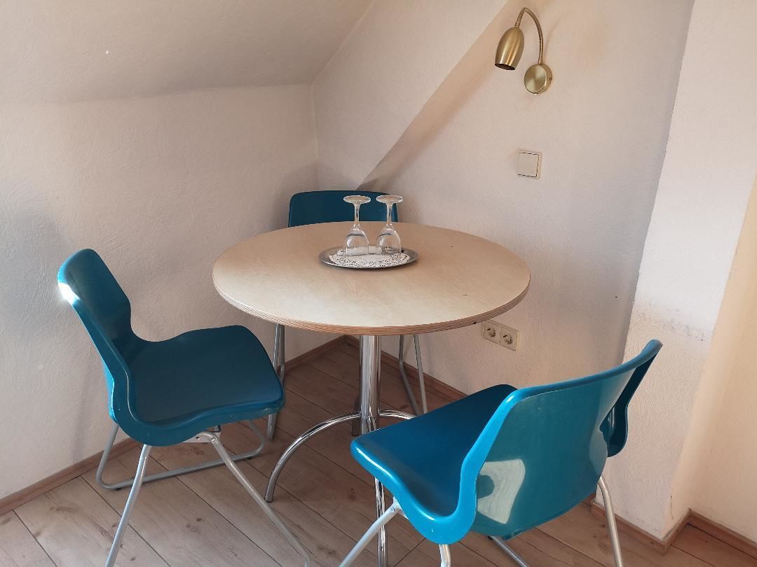A small dining area with a round table and two blue chairs.