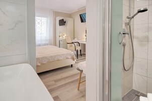 Habitación de hotel moderna con una cama grande, un escritorio y zona de ducha.
