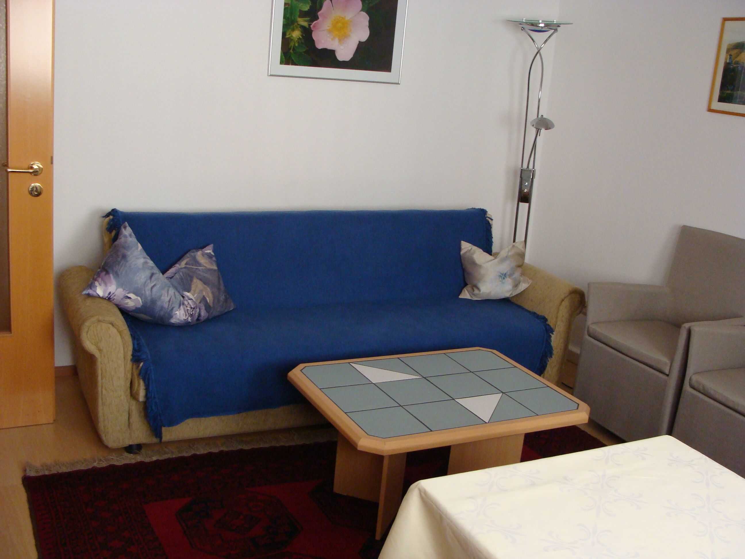 A living room with a blue sofa, a small table, and a floor lamp.