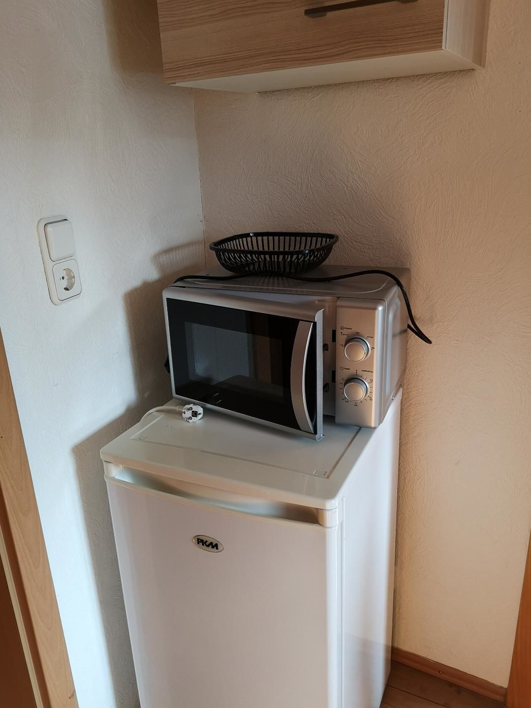 A compact kitchenette with a white refrigerator, a microwave, and a toaster.
