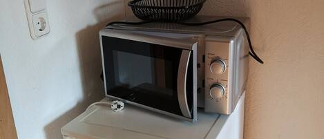 A compact kitchenette with a white refrigerator, a microwave, and a toaster.