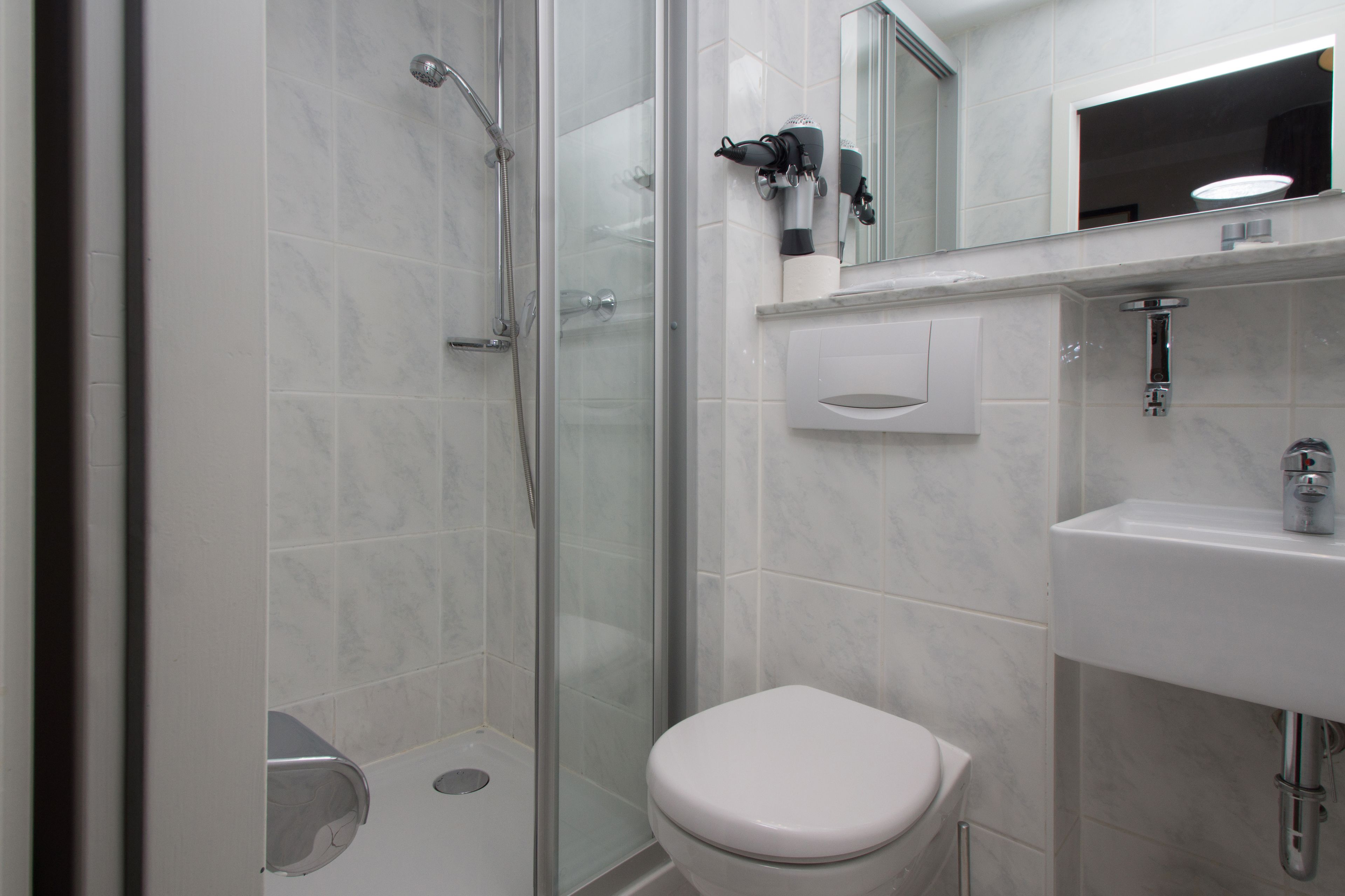 A modern bathroom with a glass-enclosed shower, a white toilet, and a sink with a mirror above it.