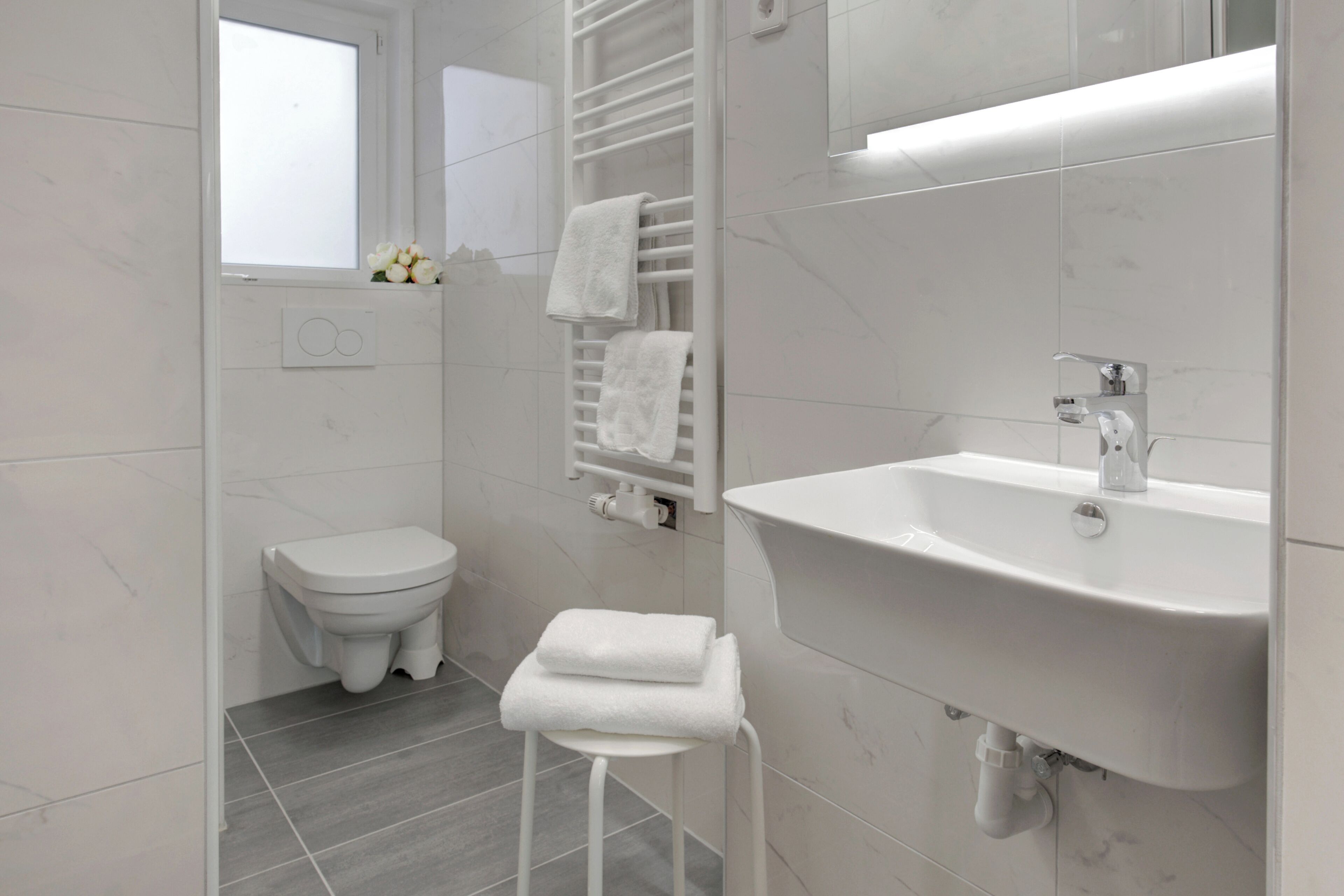 Ein modernes Badezimmer mit Toilette, Waschbecken und Handtuchhalter.