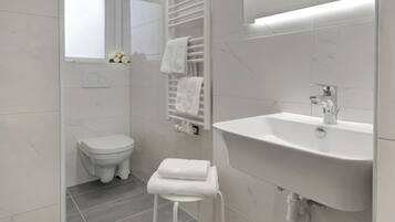 Ein modernes Badezimmer mit Toilette, Waschbecken und Handtuchhalter.
