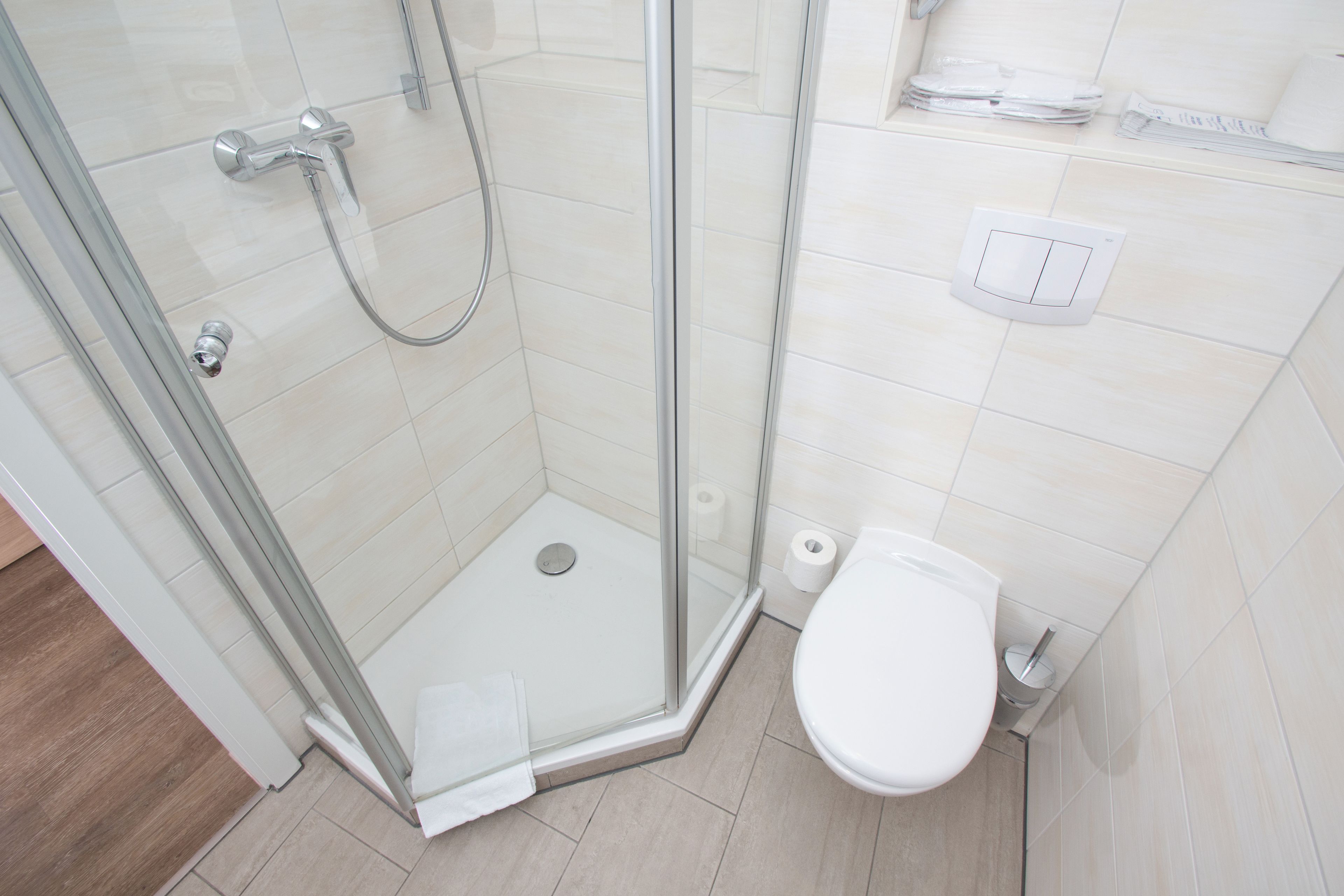 A modern bathroom with a glass-enclosed shower, a toilet, and a paper towel dispenser.
