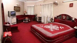 A hotel room with a large bed, a sofa, a television, and a desk. - ZUZU Hemkunt (New Delhi)