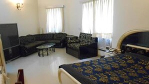 A bedroom with a large bed, a sofa, a television, and a small table. - ZUZU Hemkunt (New Delhi)