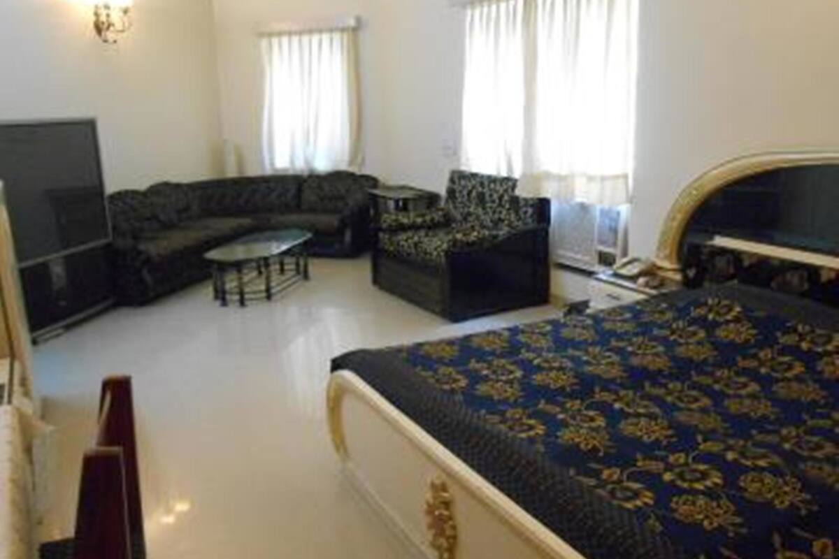 A bedroom with a large bed, a sofa, a television, and a small table.