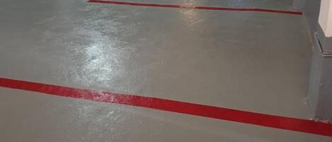 An empty parking garage with concrete pillars and red lines on the floor.