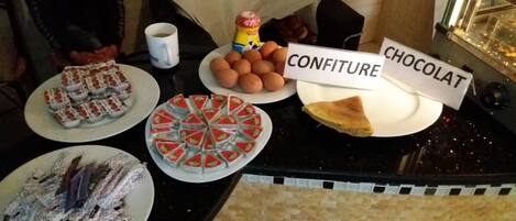 A buffet table with labeled dishes including confiture, chocolate, and other desserts.