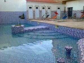 Una piscina al aire libre de temporada, sombrillas