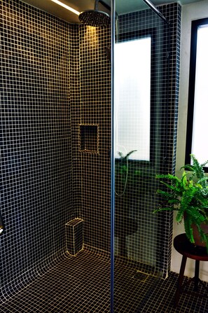 A modern bathroom with black tiled walls, a glass shower enclosure, and a potted plant. - Ananda's Siem Reap (Siem Reap)