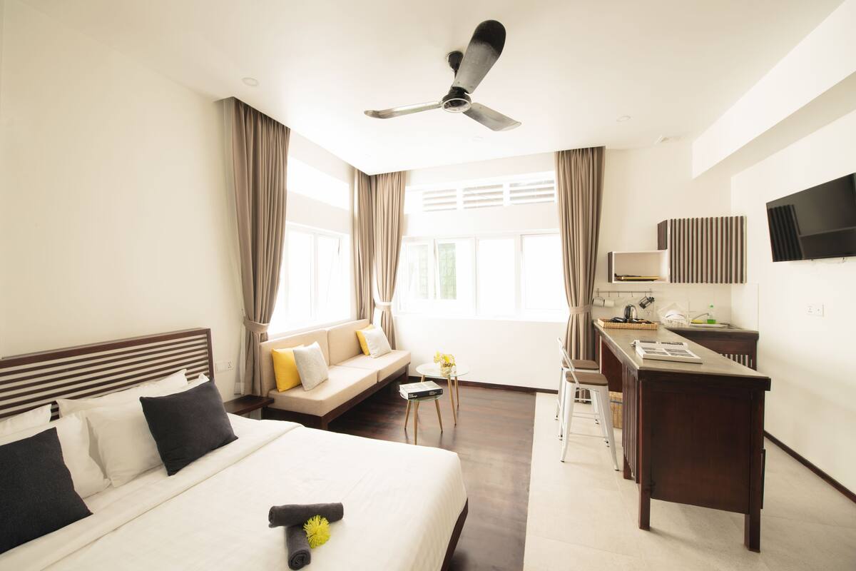 A hotel room with a bed, a desk, a sofa, and a TV.
