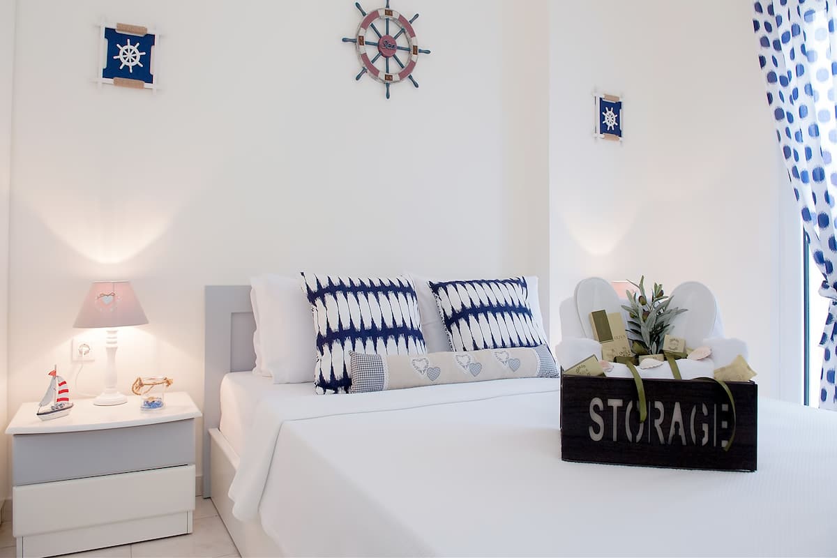 A bedroom with a bed, nightstands, a lamp, decorative pillows, wall art, and a sign.