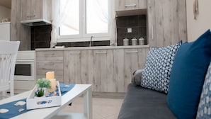 Una cocina moderna con armarios de madera, horno empotrado y ventana con cortinas translúcidas.