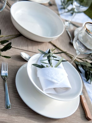 A table setting with a folded napkin, a spoon, and a fork on a wooden table. - Villa Elaia Mare (Komotini)