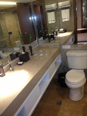A modern bathroom with a large mirror, a sink, a toilet, and a shower area. - Yiwu Wendemu International Hotel (Jinhua)